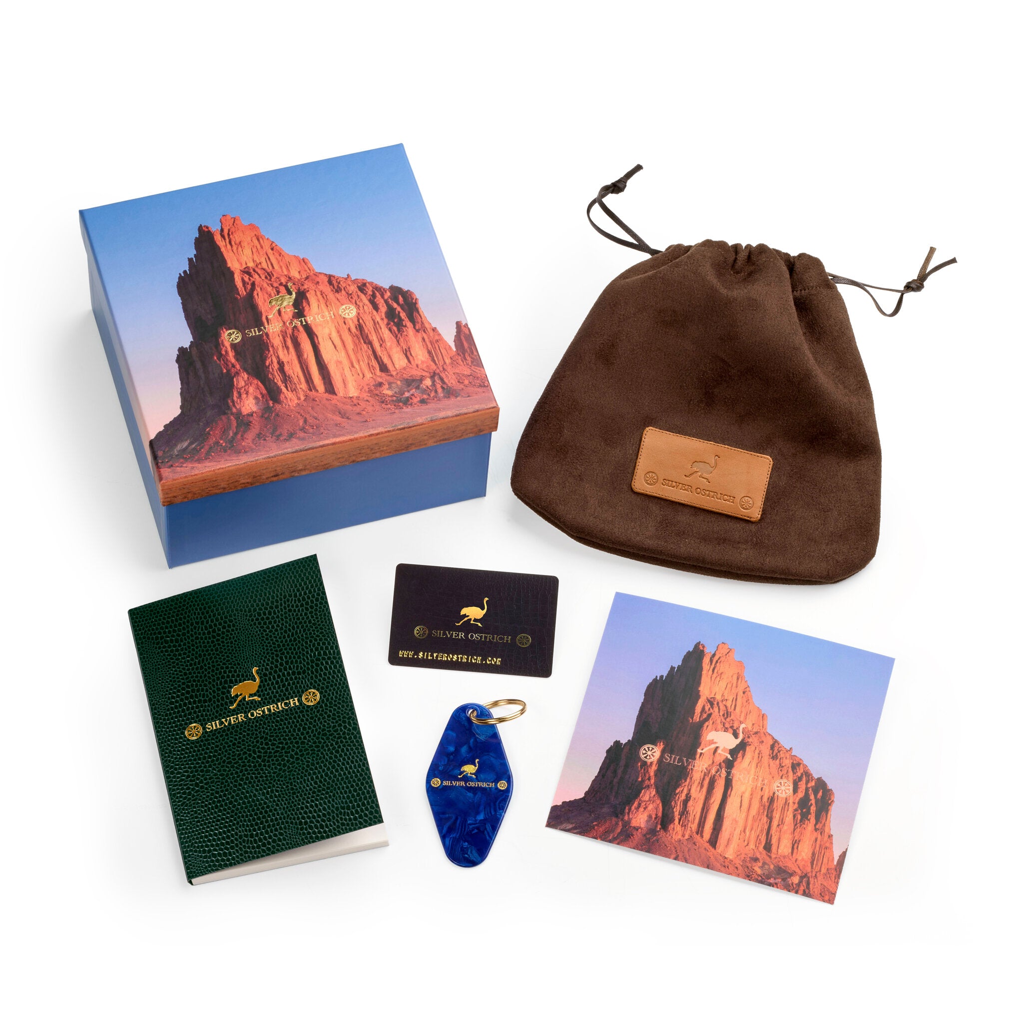 Collection of items including a box, card, keychain, and pouch with a scenic design on a white background.